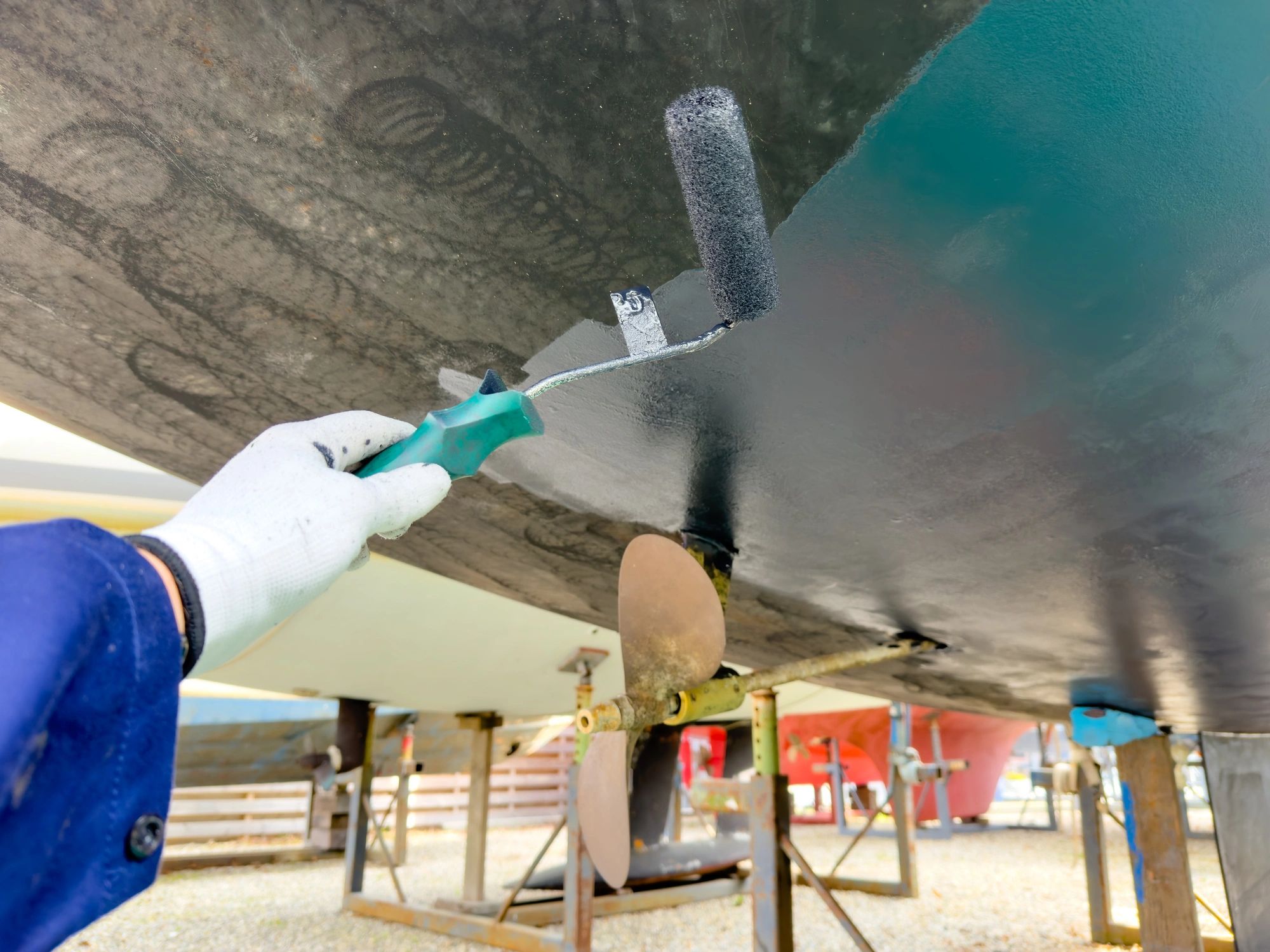 Sailing boat on stilts being painted with antifouling